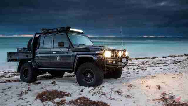 Фото Тойота Лэнд Крузер 70 Лифтованный пикап Toyota Land cruiser на больших колесах на берегу озера.