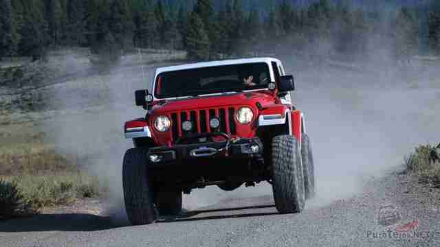 Jeep Jeepster на больших колёсах мчится по гравийной дороге Jeep Jeepster на больших колёсах мчится по гравийной дороге