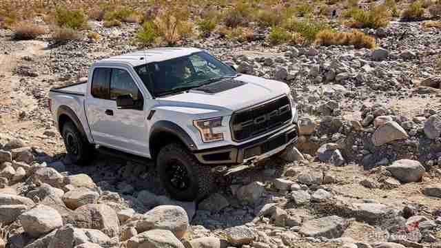 Белый Ford Раптор едет по камням