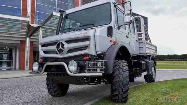 Грузовик Unimog на тротуаре у здания