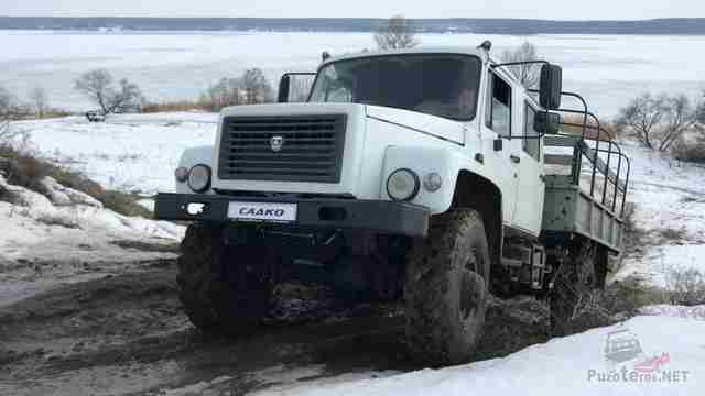Грузовой автомобиль выезжает из грязи возле зимнего озера Грузовой автомобиль выезжает из грязи возле зимнего озера