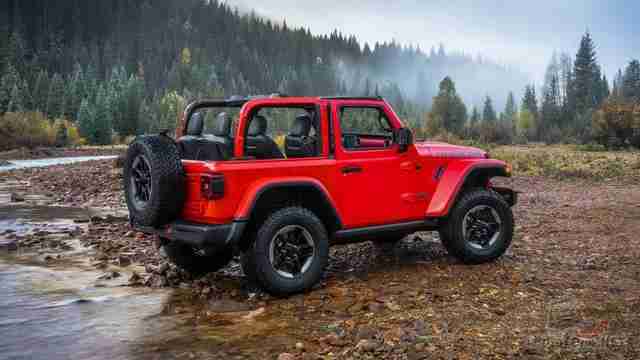 Jeep Wrangler с откидным верхом на каменистом берегу в лесу