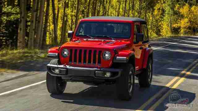 Красный Jeep Wrangler едет по шоссе в лесу