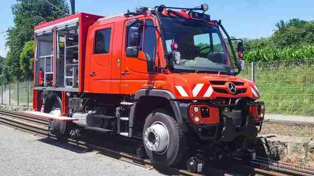 Красный локомобиль Mercedes-Benz Unimog на рельсах