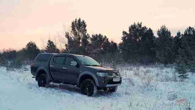 L200 предыдущего поколения с кунгом в зимнем лесу