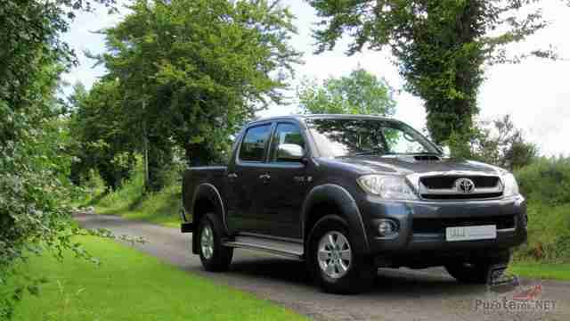 Серая Toyota Hilux едет по дороге в лесу Серая Toyota Hilux едет по дороге в лесу