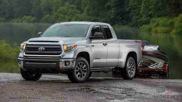 Серая Toyota Tundra на прицепе спускает катер в озеро