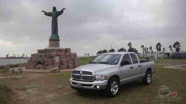 Серый Dodge Ram возле статуи Исуса