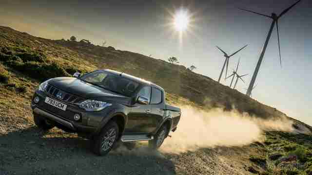 Тёмный Mitsubishi L200 едет вдоль ветряных мельниц