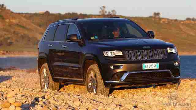 Автомобиль Джип едет по каменистому берегу озера