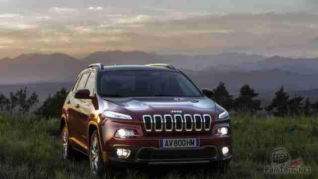 Jeep Cherokee с включенными фарами на траве