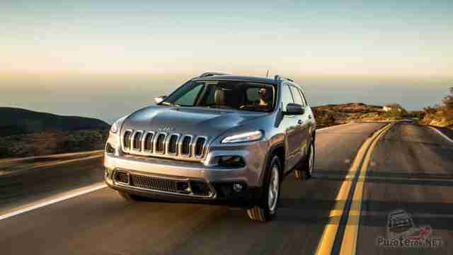Серый Jeep Cherokee едет по шоссе за городом