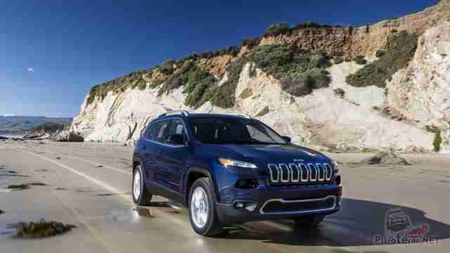 Тёмный Jeep Cherokee едет вдоль скалы