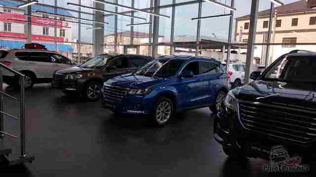 Автомобили в автосалоне возле витринного окна Автомобили в автосалоне возле витринного окна