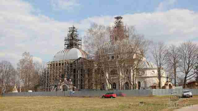 Автомобили туристов у реставрируемого здания церкви